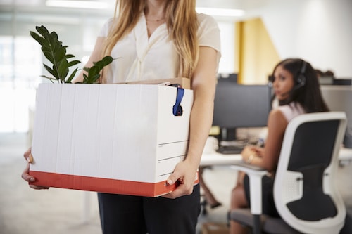 Fired female employee holding box of belongings in an office